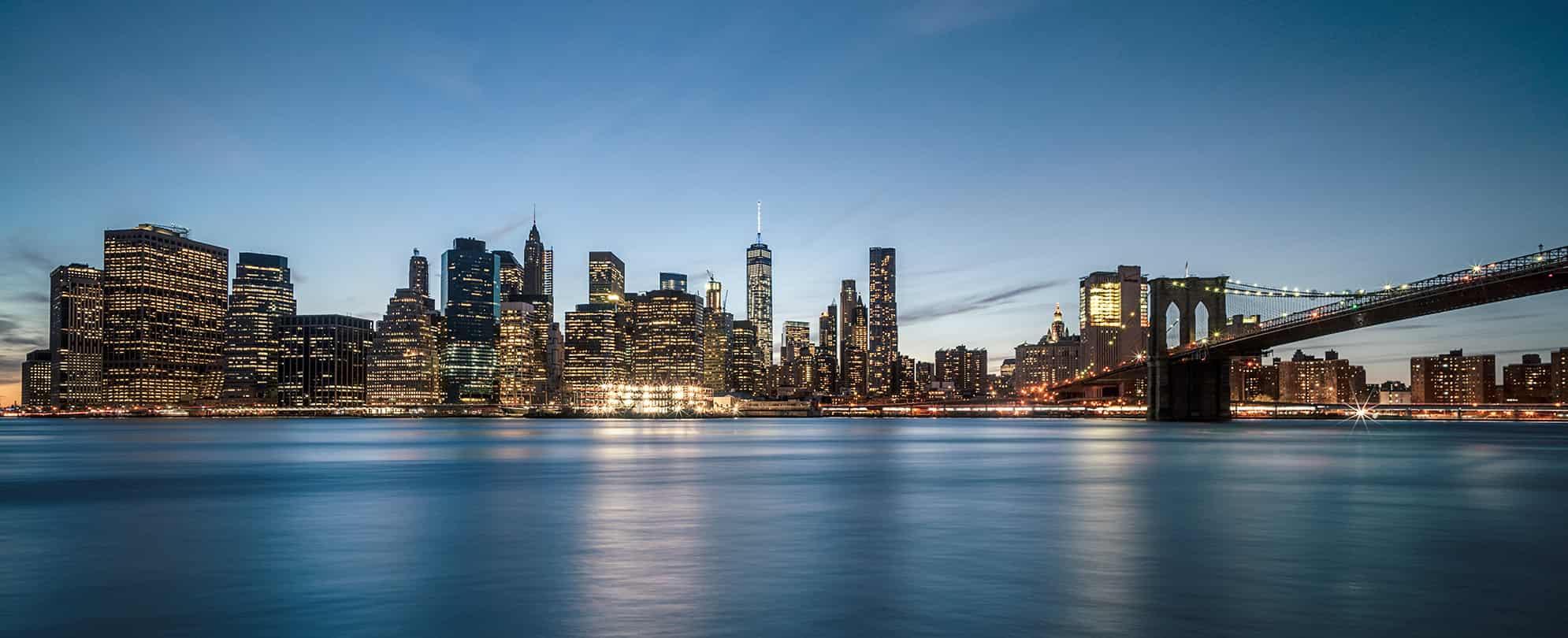 The New York City skyline, Brooklyn Bridge, and East River at dusk