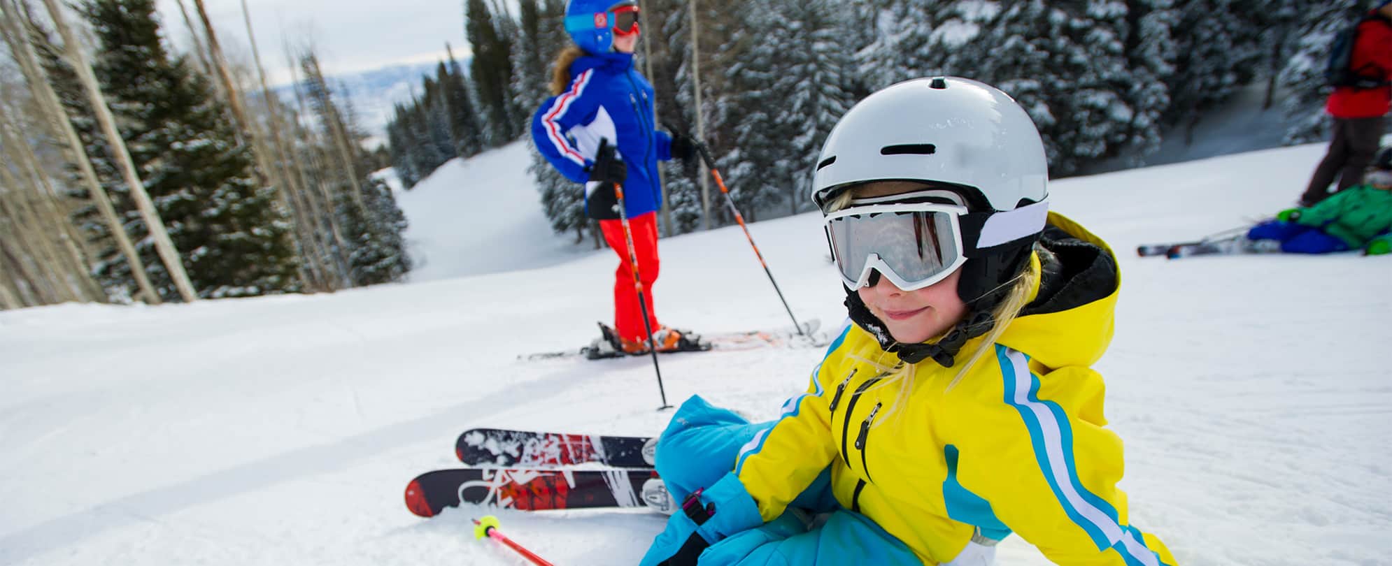 Young kids in goggles, helmets, and ski gear enjoy skiing in Park City, Utah.