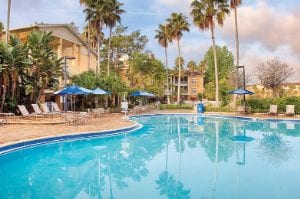 Outdoor resort pool surrounded by pool chairs and palm trees at Club Wyndham Cypress Palms, a timeshare resort in Kissimmee, FL.